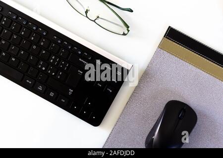 Workstation vuoto con tastiera, mouse pad e bicchieri Foto Stock