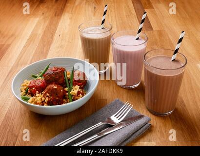 Contenuto calorico controllato quotidianamente servizio ristorazione, inclusa colazione frullato, uno snack e pasti serali di deliziose polpette di carne, girato su un sfondo di legno Foto Stock