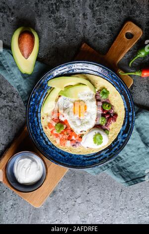 Deliziosa Huevos Rancheros Tostadas, colazione messicana consistente di tortilla tostato, pomodoro tagliato a pezzetti e la cipolla, jalapeno e fagiolo mash, guarnita con f Foto Stock