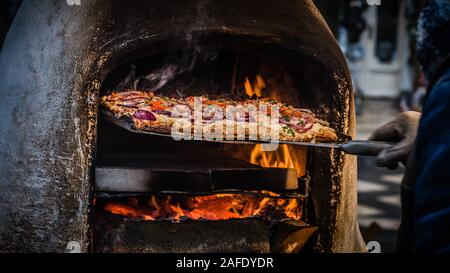 L'uomo rimozione appena fatti strada pizza cibo dal forno a legna in Budapest Foto Stock