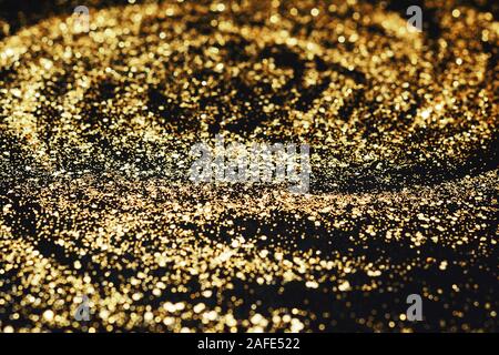 Golden glitter su sfondo nero, vista dall'alto. Abstract pattern creato a mano, imitaion di tempesta, il fuoco selettivo Foto Stock