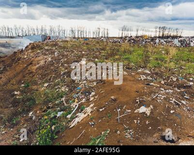 La grande heap dump di rifiuti si estende parallelamente al fiume,Garbage montagne con cielo nuvoloso di massa indietro in giorno luce,rifiuti ha prodotti petroliferi sono Foto Stock