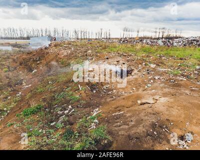 La grande heap dump di rifiuti si estende parallelamente al fiume,Garbage montagne con cielo nuvoloso di massa indietro in giorno luce,rifiuti ha prodotti petroliferi sono Foto Stock