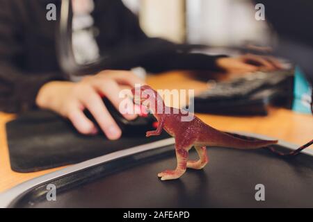 Le riprese Tirannosauro T-rex dinosauro contro lo sfondo di un programmatore a un computer Foto Stock