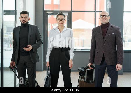 Gruppo di eleganti viaggiatori di affari di diverse etnie e età in aeroporto Foto Stock