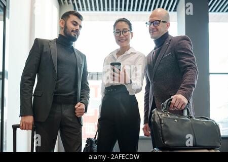 Gruppo di colleghi in viaggio alla ricerca per il modo giusto di hotel in rete Foto Stock