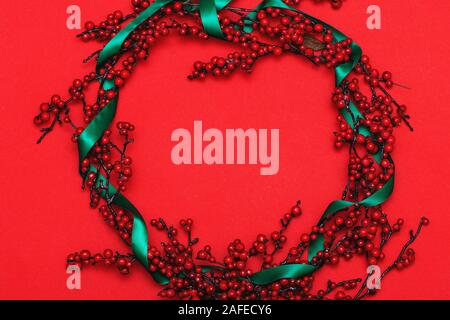 Ghirlanda di Natale con nastro verde su sfondo rosso. Foto Stock