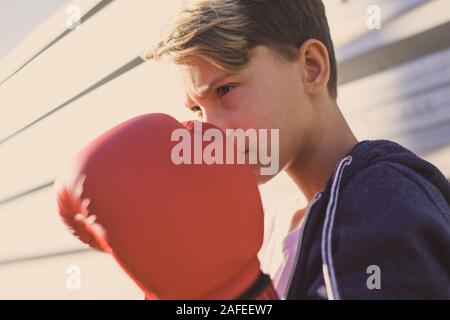 Ritratto di bel giovane maschio con i guantoni davanti al viso. Ragazzo pronto per un allenamento boxe per difendere la testa con le mani. Boxer pronti a gettare pu Foto Stock