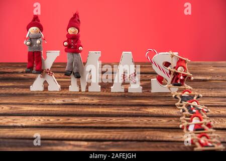 Lettere di legno formando parola XMAS con nastri e figure rosse di bambole oltre a loro. La bambola di sale la scaletta di corda a lettere Foto Stock