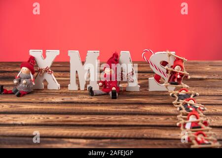 Lettere di legno formando parola XMAS con nastri e figure rosse di bambole oltre a loro. La bambola di sale la scaletta di corda a lettere Foto Stock