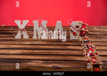 Lettere di legno formando parola XMAS con nastri e figure rosse di bambole oltre a loro. La bambola di sale la scaletta di corda a lettere Foto Stock