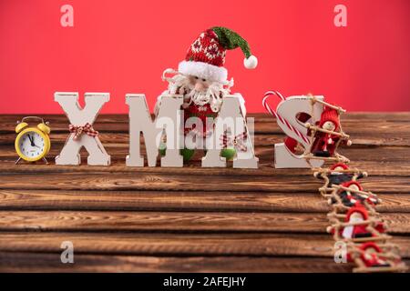 Lettere di legno formando parola XMAS con nastri e figure rosse di bambole oltre a loro. La bambola di sale la scaletta di corda a lettere Foto Stock