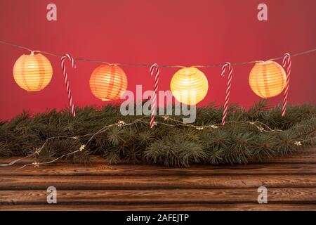 Composizione di natale. Ghirlanda di Natale, Abete rami di legno e lo sfondo rosso. copia di spazio. Foto Stock