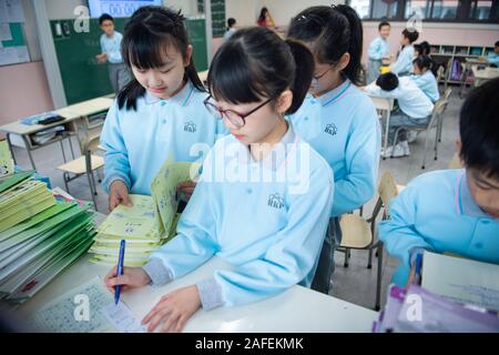 (191215) -- MACAO, Dic 15, 2019 (Xinhua) -- Yu nel peccato (1L, anteriore) e i suoi compagni di scuola organizzare l'esercizio libri presso l'aula della Scuola di Premier affiliate a Hou Kong Middle School di Macao, Cina del sud, nov. 25, 2019. Il 10-anno-vecchio Yu, nato a Macao, è un quinto grado di studente della Scuola di Premier affiliate a Hou Kong scuola media. Suo fratello anche gli studi presso la scuola. Agli occhi di sua madre, Yu nel peccato è un ottimista, soleggiata e vivace ragazza con molti talenti. Ha vinto molti premi in Macao studenti della scuola primaria' storytelling, recita, arte e competizioni di ballo Foto Stock