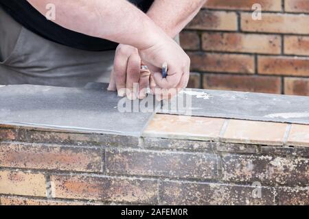 L'installatore le misure e le mette segni per il taglio e la posa di un tile Foto Stock