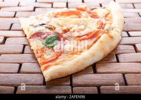 Trancio di pizza italiana su un supporto in legno Foto Stock