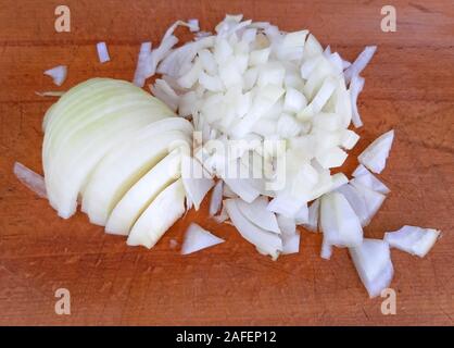 La cipolla sbucciata e tagliata su uno sfondo di legno Foto Stock