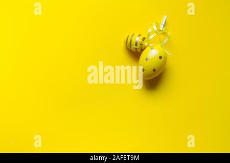 Decorazione di Pasqua, due giallo uova decorativi cuciti insieme con nastri su un brillante sfondo giallo Foto Stock