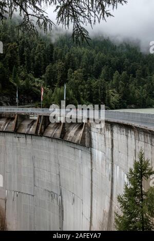 Gli escursionisti guardando giù il 74 metro alto Zmuttbach arch dam in alto nelle Alpi Svizzere vicino a Zermatt Foto Stock