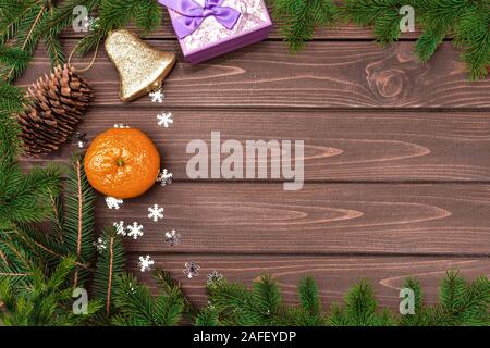 Sfondo di Natale Abete rami, coni , arancione, Campana e doni su un tavolo di legno. Spazio per il testo. Vista da sopra. Atmosfera natalizia Foto Stock