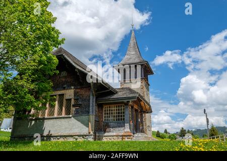 Incantevole vecchia chiesa con artigianali a scandole di legno sulle pareti esterne nella località di Les muschi, Vaud, Svizzera Foto Stock