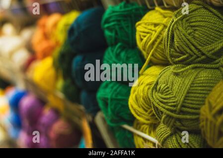 Matasse colorate di lana su uno scaffale di un negozio. Matasse di lana per maglieria di tutti i colori dell'arcobaleno, blu, verde, marrone, giallo, rosso e viola. Foto Stock