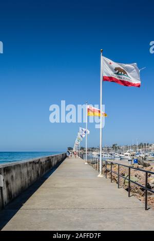 Una diminuzione in prospettiva della scogliera lungomare accanto a una sfilata di bandiere a Santa Barbara Porto di Santa Barbara, CA, Stati Uniti d'America Foto Stock