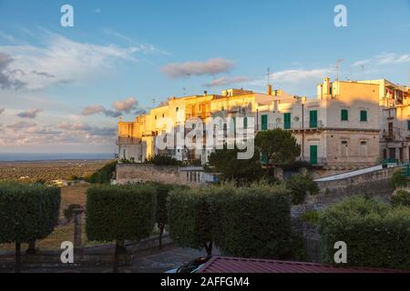 Gli edifici di vecchia costruzione nella storica città di collina di Ostuni nel distretto di Brindisi, puglia, Italia meridionale, illuminate da soft golden ora estate luce della sera Foto Stock