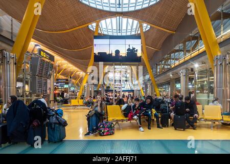 I clienti siedono sui banchi del Terminal 4 di Madrid Barajas Adolfo Suárez aeroporto a Madrid, Spagna. Foto Stock