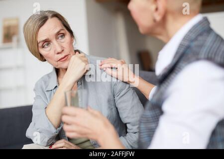 Ritratto di donna matura guardando psicologo femmina che offre un bicchiere di acqua durante la sessione di terapia, spazio di copia Foto Stock