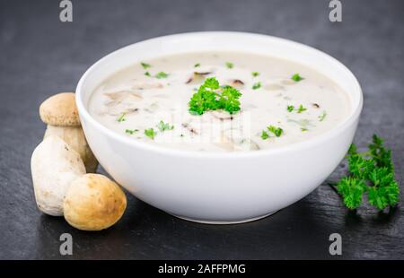 Zuppa di porcini su un vintage lastra di ardesia come dettagliato di close-up shot; messa a fuoco selettiva Foto Stock