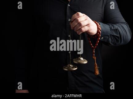 Rame Kartaly tibetano detiene mano d'uomo su uno sfondo scuro, close up Foto Stock