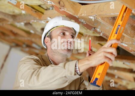 Lavoratore verificare il livello di casa in legno struttura Foto Stock