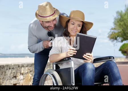 Matura in sedia a rotelle che guarda al mare Foto Stock