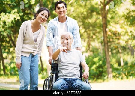 Giovani asiatici giovane e sedia a rotelle padre legato di relax all'aperto nel parco Foto Stock