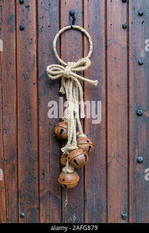 Natale sleigh bells su una vecchia casa in legno porta in Chipping Campden, Cotswolds, Gloucestershire, Inghilterra Foto Stock