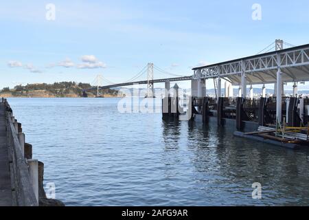 San Francisco Bay Bridge attraversa l'isola del tesoro, visibile sulla sinistra. Preso da Pier 14, capolinea della linea Alameda della baia di traghetti. Foto Stock