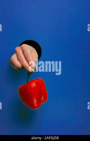 Mano femminile in un foro circolare in blu sullo sfondo di trend Foto Stock