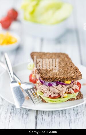 Tonno Sandwich (pane; il fuoco selettivo) su un vecchio tavolo in legno Foto Stock