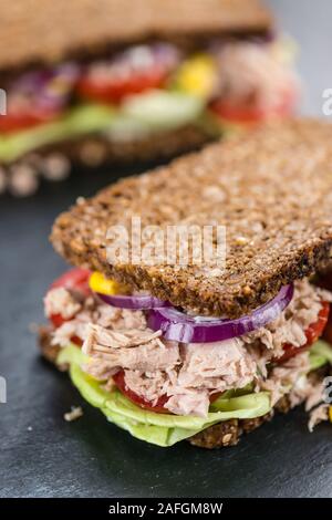 Lastra di ardesia con un sandwich di tonno (pane; il fuoco selettivo; close-up shot) Foto Stock