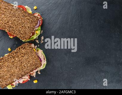 Lastra di ardesia con un sandwich di tonno (pane; il fuoco selettivo; close-up shot) Foto Stock