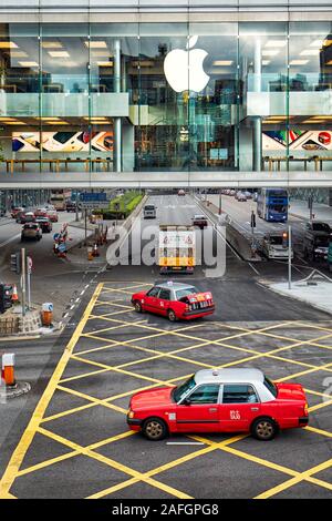 Red taxi passando dagli Apple Store in centrale. Hong Kong, Cina. Foto Stock