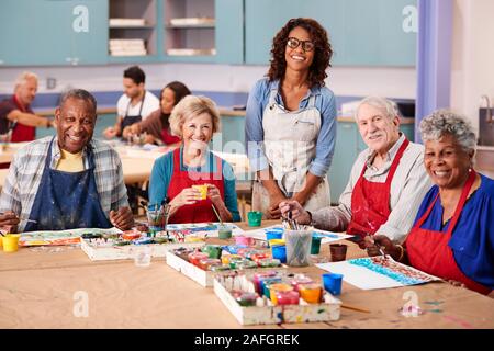 Ritratto di pensionati anziani che frequentano la classe d'arte nel centro comunitario con l'insegnante Foto Stock