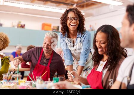Gruppo di adulti maturi che frequentano la classe d'arte nel centro comunitario con l'insegnante Foto Stock