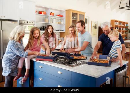 Multi generazione Famiglia intorno a Isola per cucina mangiare pizza da asporto insieme Foto Stock