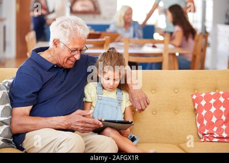 Nonno seduto con il nipote sul divano con tavoletta digitale in casa Foto Stock