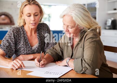 Amico femminile aiutando donna Senior per completare l'ultima volontà e testamento a casa Foto Stock