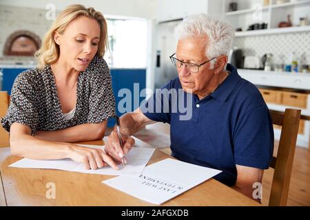 La donna aiuta l uomo Senior per completare l'ultima volontà e testamento a casa Foto Stock