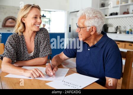 La donna aiuta l uomo Senior per completare l'ultima volontà e testamento a casa Foto Stock