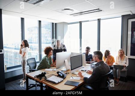 Attività Creative team lavorano insieme in un affollato ufficio casual Foto Stock